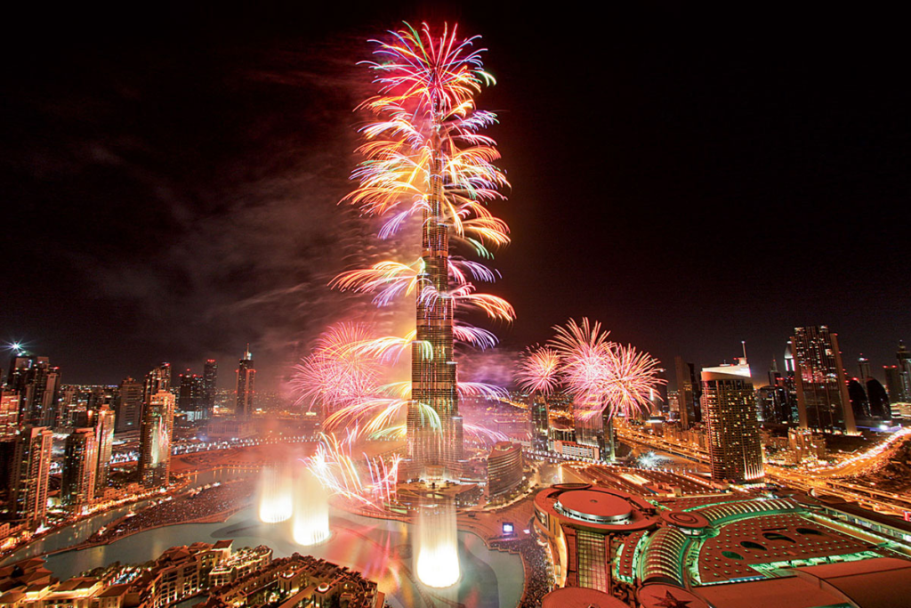 Crowds watching Burj Khalifa lit by fireworks over Downtown Dubai at night
