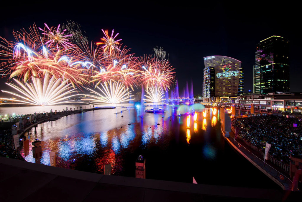 Crowds watching Burj Khalifa lit by fireworks over Downtown Dubai at night