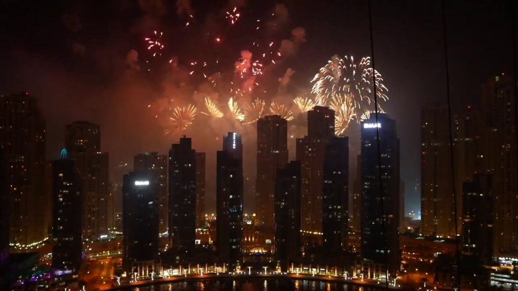 Crowds watching Burj Khalifa lit by fireworks over Downtown Dubai at night